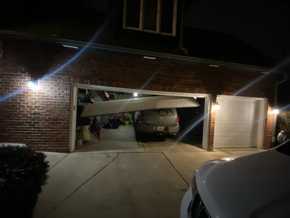 Garage door that has come off its track, at night